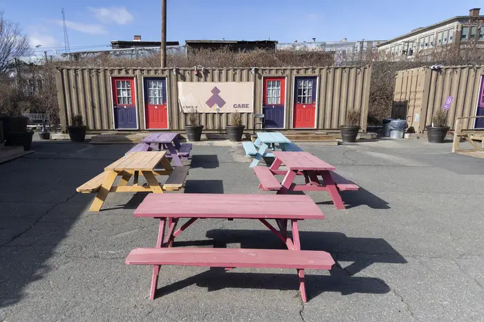 Picnic benches in front of a shipping container.